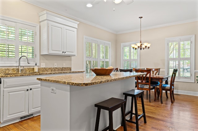 1096 Dunham Rd, Orangeburg, SC 29118 - kitchen featuring light stone countertops, a breakfast bar, ornamental molding, a sink, and white cabinetry