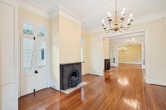 unfurnished living room featuring an inviting chandelier, hardwood / wood-style flooring, and crown molding