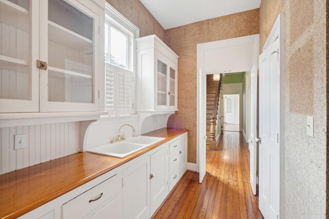 kitchen with sink, white cabinets, wood counters, and dark wood-type flooring