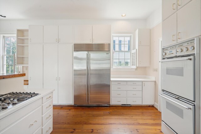 kitchen featuring appliances with stainless steel finishes, light hardwood / wood-style flooring, white cabinets, and a healthy amount of sunlight