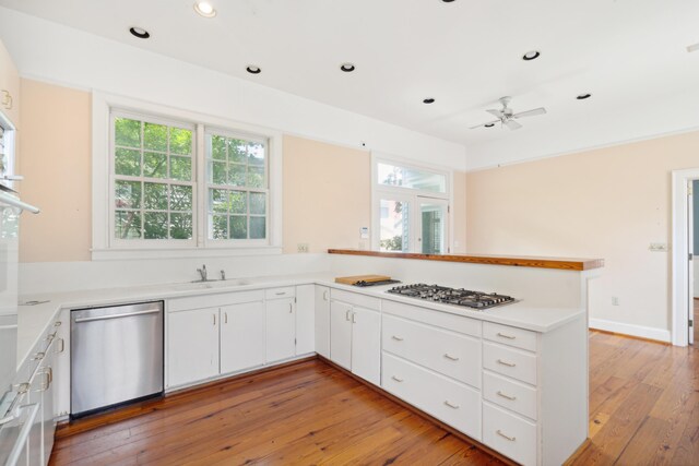 kitchen with ceiling fan, stainless steel appliances, light hardwood / wood-style floors, and kitchen peninsula