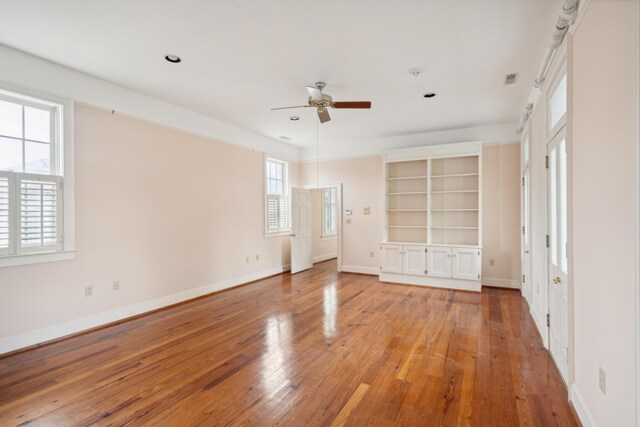 unfurnished bedroom with multiple windows, hardwood / wood-style floors, and ceiling fan