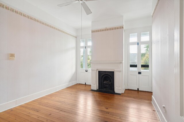 unfurnished living room with ceiling fan and hardwood / wood-style floors