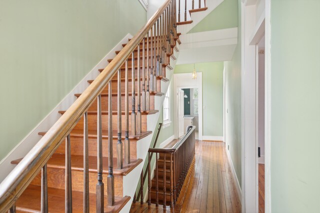 stairway featuring wood-type flooring and a towering ceiling