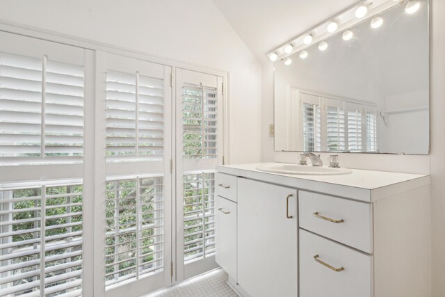 bathroom with tile patterned floors, vanity, lofted ceiling, and a healthy amount of sunlight