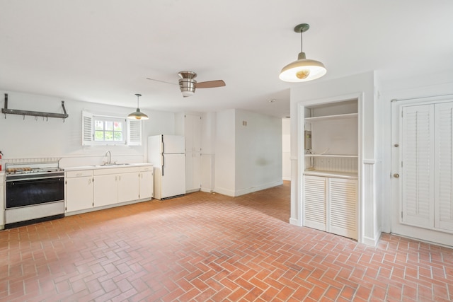 kitchen featuring white fridge, decorative light fixtures, white cabinetry, sink, and stove