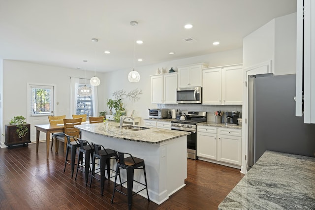 310 Silent Bluff Dr, Summerville, SC 29486 - kitchen featuring white cabinets, an island with sink, light stone counters, decorative light fixtures, and stainless steel appliances