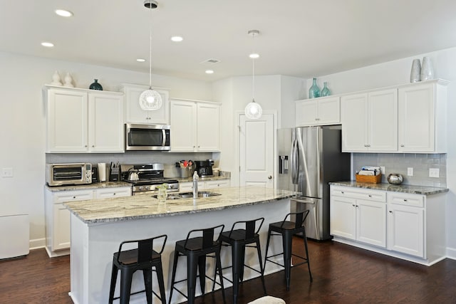 310 Silent Bluff Dr, Summerville, SC 29486 - kitchen with decorative light fixtures, stainless steel appliances, a kitchen island with sink, a sink, and white cabinetry