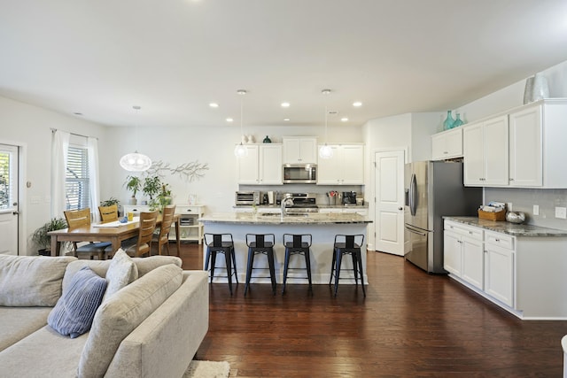 310 Silent Bluff Dr, Summerville, SC 29486 - kitchen with light stone counters, open floor plan, hanging light fixtures, a kitchen island with sink, and stainless steel appliances