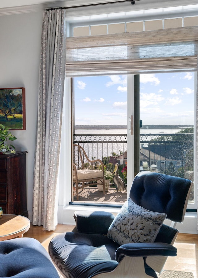 sitting room with crown molding, a water view, and wood finished floors