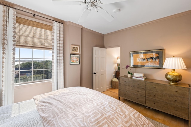 bedroom with ornamental molding, a ceiling fan, and wood finished floors