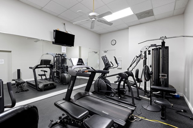 workout area with baseboards, ceiling fan, and a paneled ceiling