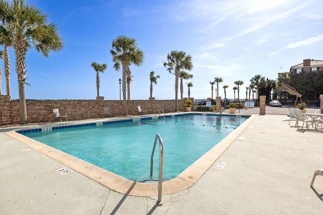 pool featuring fence and a patio area