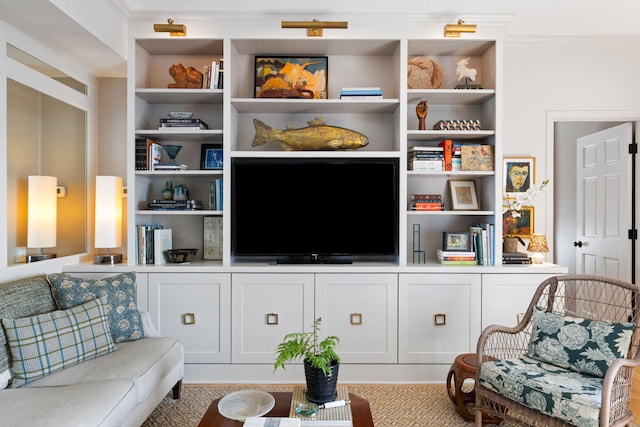 living area featuring crown molding and built in shelves