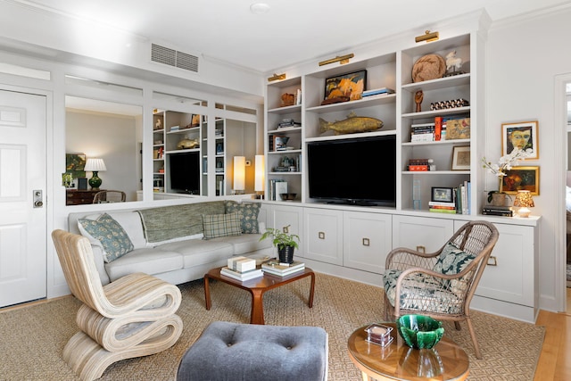 living area with visible vents, ornamental molding, and built in shelves