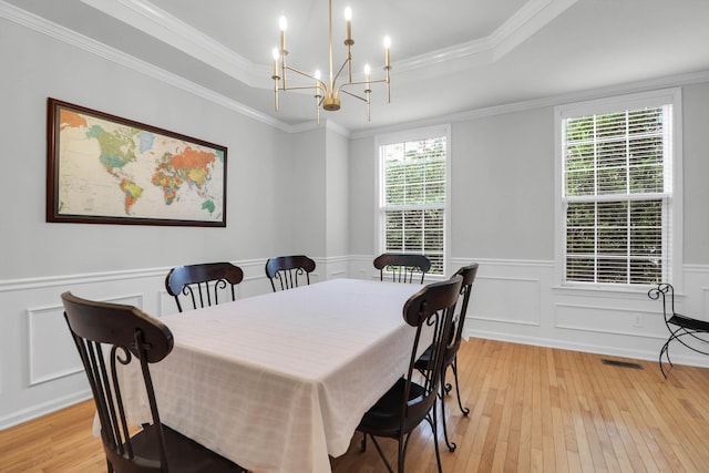 200 Oak Point Landing Dr, Mount Pleasant, SC 29464 - dining area with light wood-style flooring, a chandelier, a raised ceiling, wainscoting, and ornamental molding