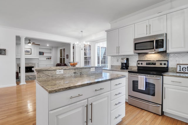 200 Oak Point Landing Dr, Mount Pleasant, SC 29464 - kitchen with appliances with stainless steel finishes, light wood finished floors, a kitchen island, a premium fireplace, and tasteful backsplash