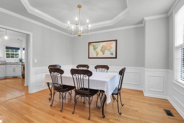 200 Oak Point Landing Dr, Mount Pleasant, SC 29464 - dining area featuring light wood-type flooring, a tray ceiling, a chandelier, a wainscoted wall, and ornamental molding