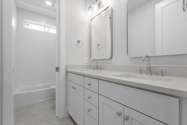 full bath with double vanity, a sink, toilet, and tile patterned floors