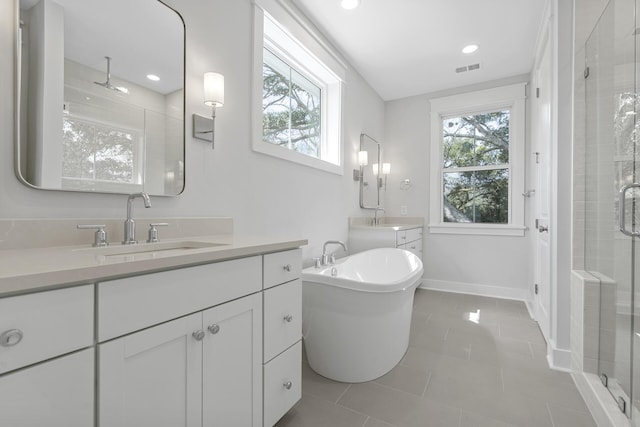 bathroom with a freestanding tub, tile patterned flooring, a sink, baseboards, and a shower stall