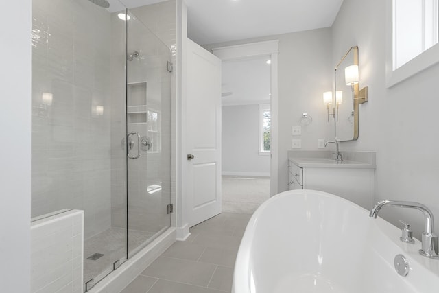 bathroom with a soaking tub, a stall shower, vanity, baseboards, and tile patterned floors