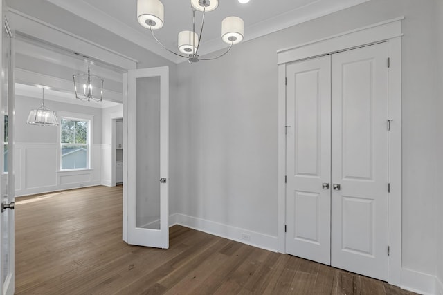 unfurnished dining area with a wainscoted wall, ornamental molding, a decorative wall, and wood finished floors