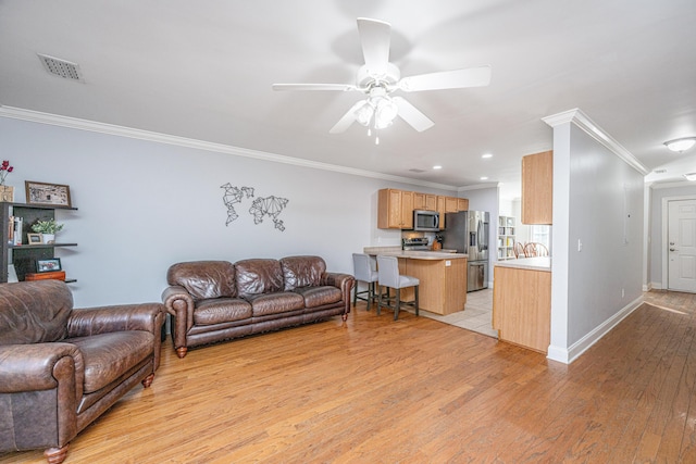 living room featuring ceiling fan, ornamental molding, and light wood-type flooring