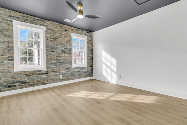 spare room with ceiling fan, light hardwood / wood-style flooring, and brick wall