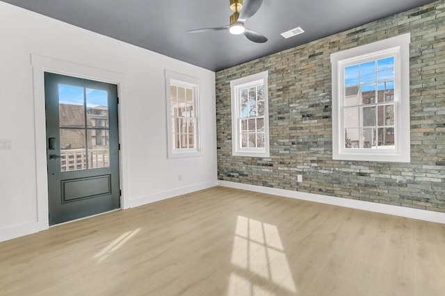 spare room featuring ceiling fan, brick wall, and light hardwood / wood-style floors