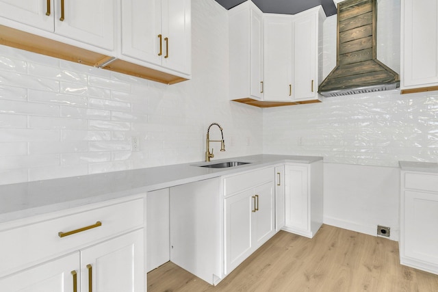 kitchen with white cabinets, wall chimney exhaust hood, and sink