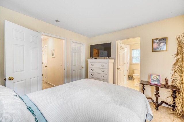 bedroom featuring light carpet and connected bathroom