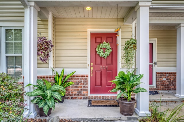 view of exterior entry with brick siding and covered porch