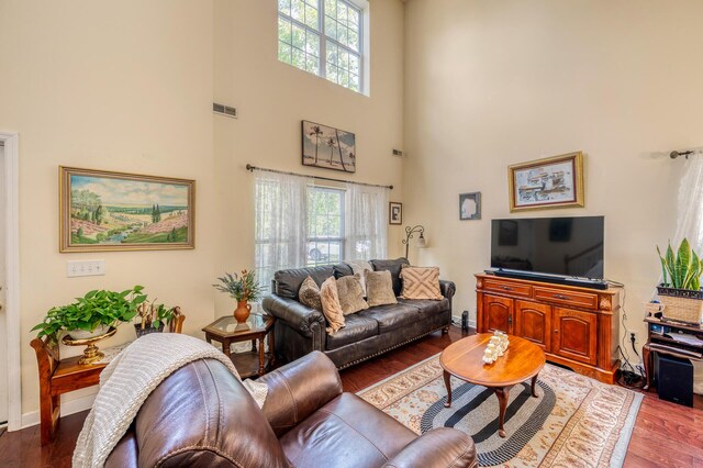 living room with dark wood-type flooring and a high ceiling