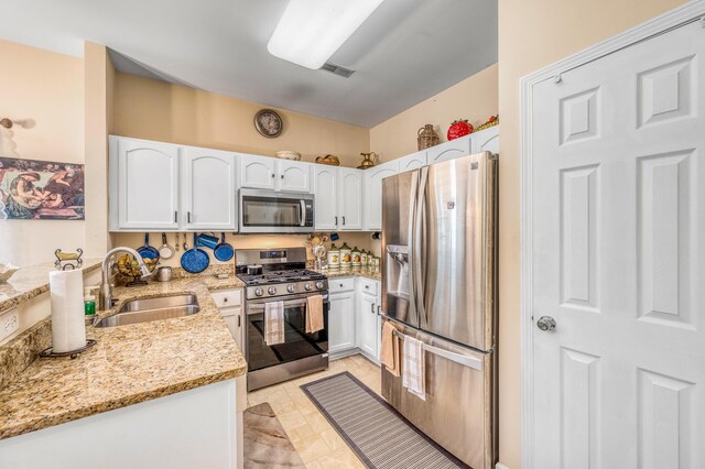 kitchen featuring light tile patterned floors, stainless steel appliances, sink, white cabinetry, and light stone counters