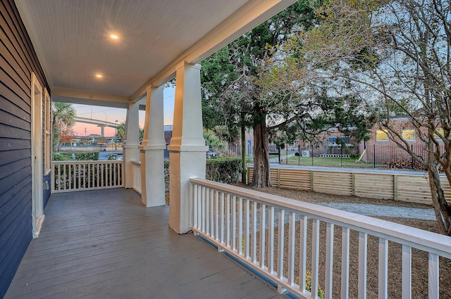 deck at dusk featuring a porch