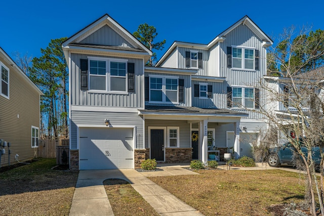 view of front of home with a garage, concrete driveway, a porch, a front lawn, and board and batten siding