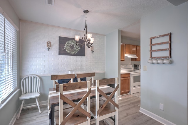 dining area featuring a textured ceiling, light hardwood / wood-style flooring, and a notable chandelier