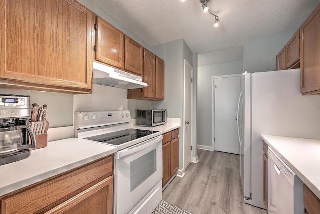 kitchen with a textured ceiling, white appliances, and light hardwood / wood-style flooring