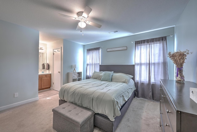 carpeted bedroom with multiple windows, a textured ceiling, connected bathroom, and ceiling fan