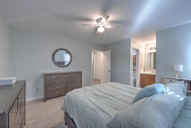 bedroom featuring ensuite bath, ceiling fan, light colored carpet, and a textured ceiling