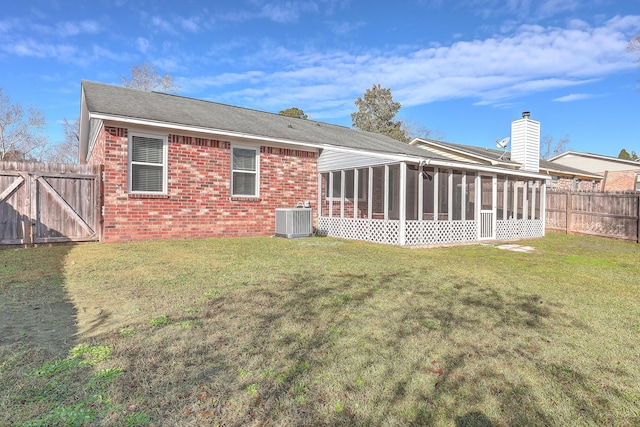 rear view of property with a sunroom, a yard, and cooling unit