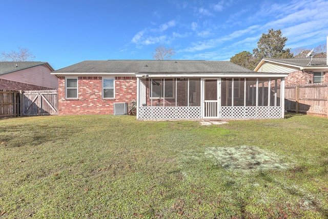 rear view of house with central air condition unit, a sunroom, and a yard