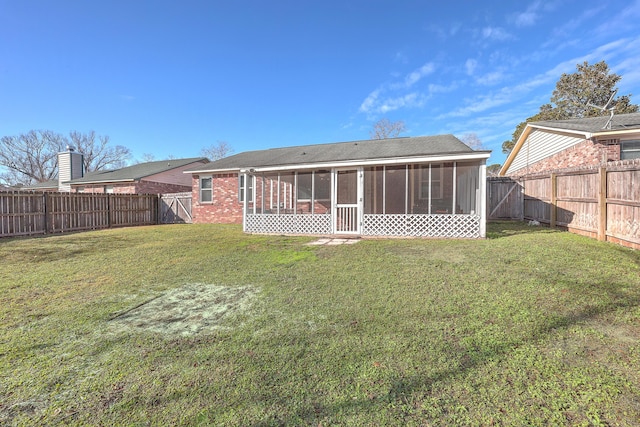 rear view of house with a lawn and a sunroom