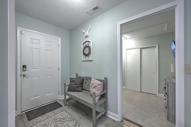 foyer entrance featuring light colored carpet and a textured ceiling