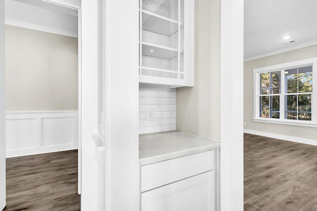 bar with crown molding, dark hardwood / wood-style flooring, tasteful backsplash, and white cabinets