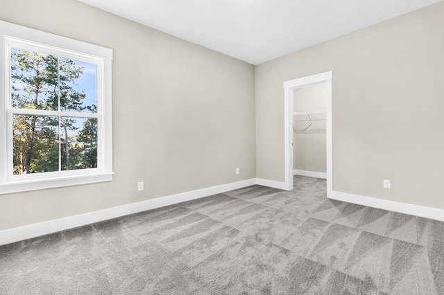 unfurnished bedroom featuring light colored carpet, a spacious closet, and a closet