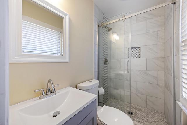 bathroom with a shower with door, vanity, and toilet