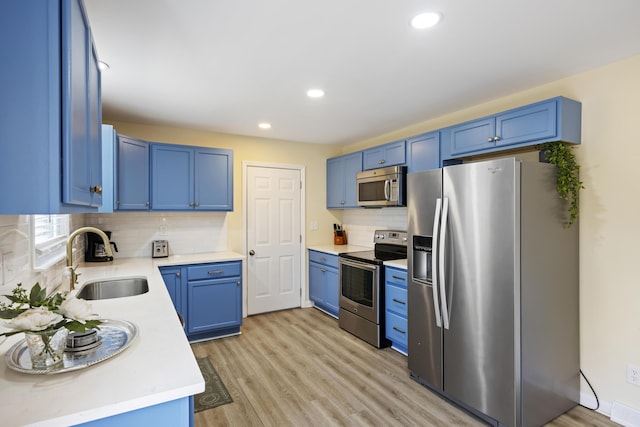 kitchen with tasteful backsplash, sink, stainless steel appliances, blue cabinetry, and light hardwood / wood-style flooring