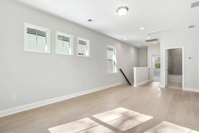 empty room featuring baseboards, attic access, light wood-style flooring, and visible vents