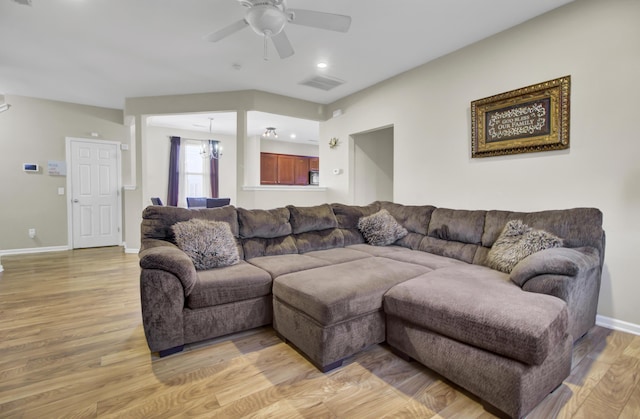 living room featuring ceiling fan with notable chandelier and light hardwood / wood-style flooring